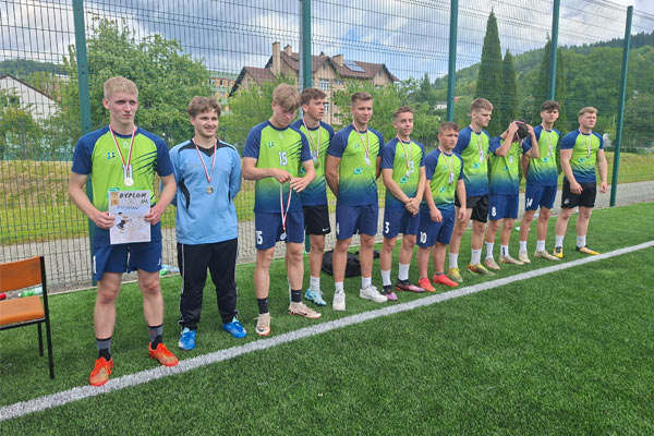 Uczniowie w sportowych koszulkach stoją na boisku