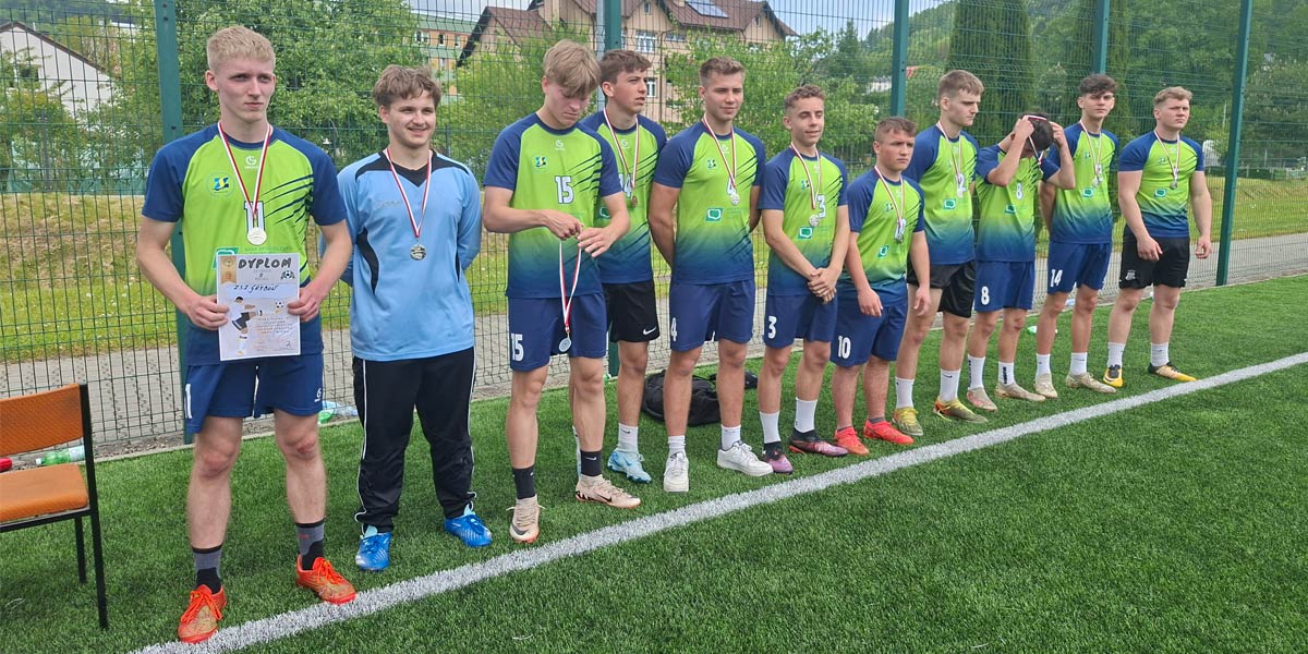 Uczniowie w sportowych koszulkach stoją na boisku