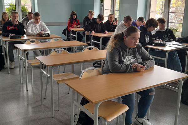 Uczniowie siedzą w sali