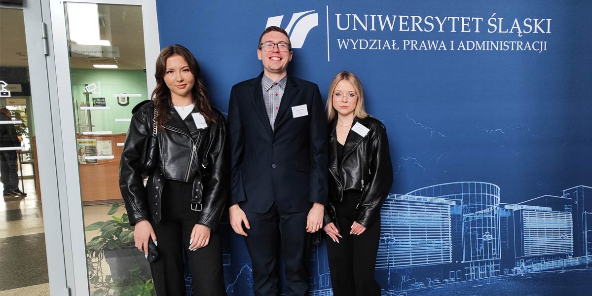 Dwie uczennice stoją z nauczycielem