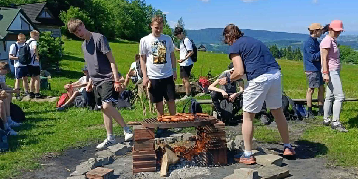 Pieczenie kiełbasy na ognisku przez uczniów.