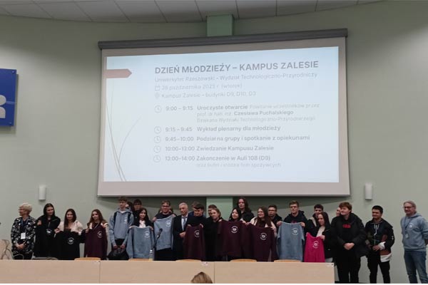 Uczniowie stoją pod tablicą projekcyjną